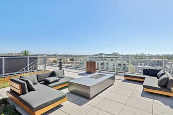 A rooftop patio with a fire pit and seating area.